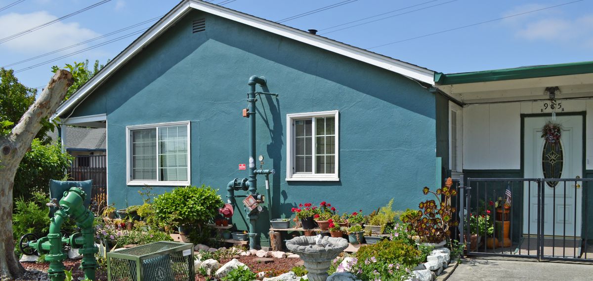 A blue house with a well-maintained garden in front.