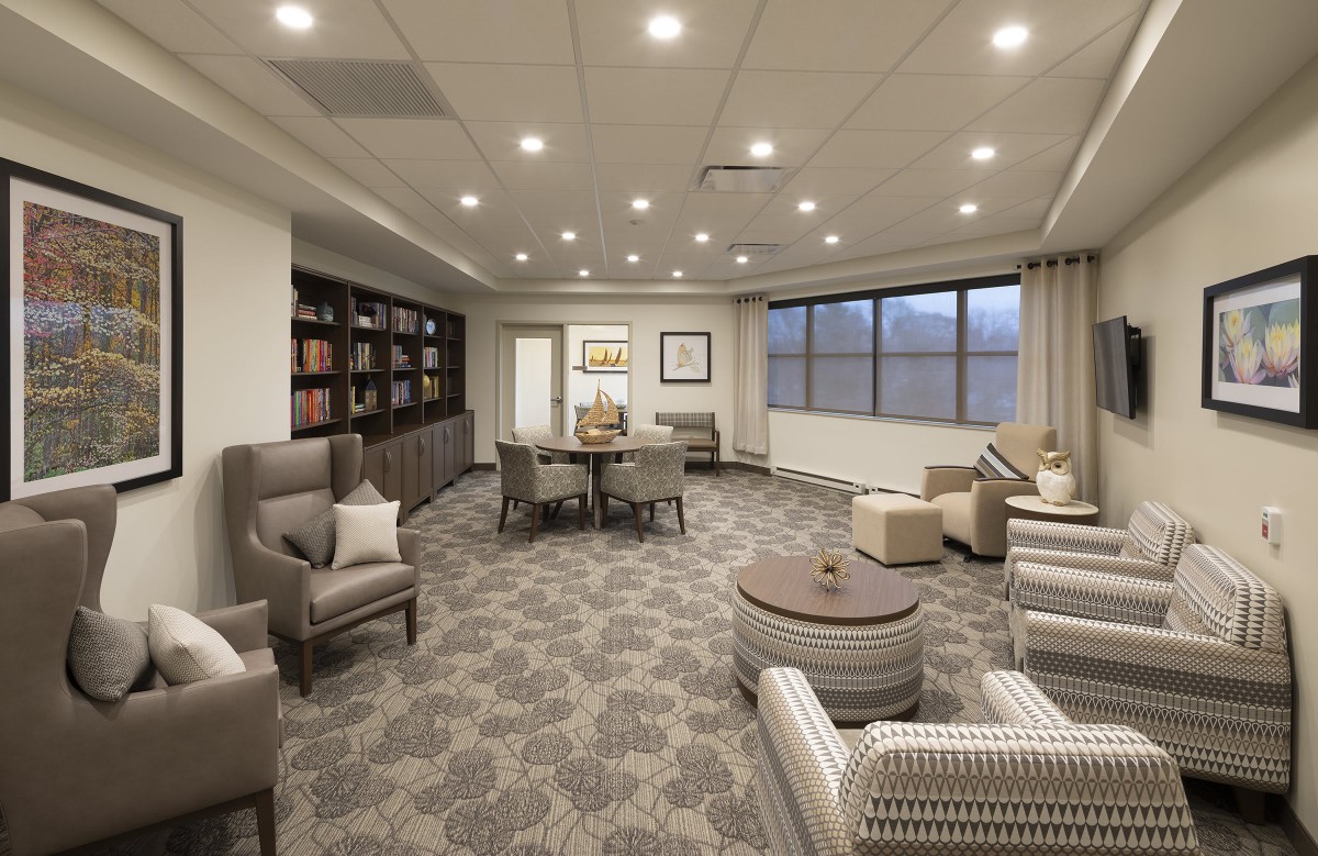 A modern lounge area with comfortable seating, bookshelves, and elegant lighting.