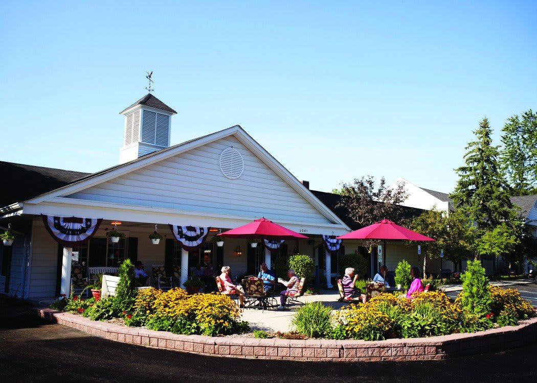 A charming outdoor patio area with red umbrellas and people enjoying a sunny day.