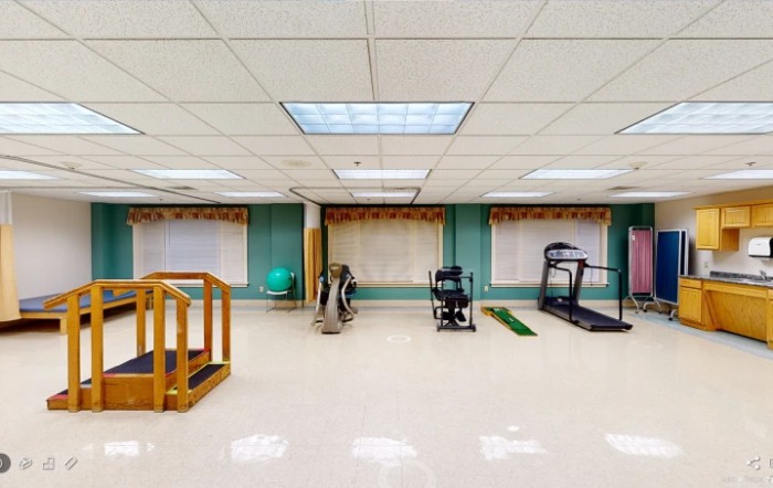An indoor gym with various exercise equipment including a treadmill and physical therapy tools.