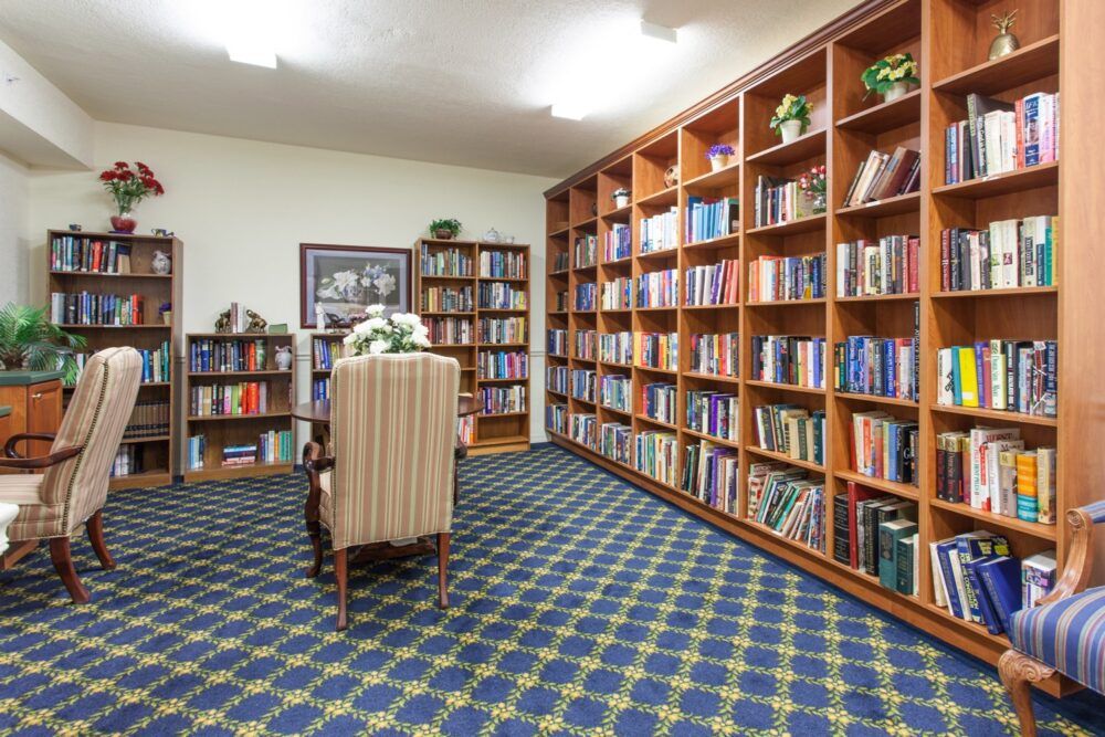A cozy library room with bookshelves filled with books and a comfortable chair for reading.