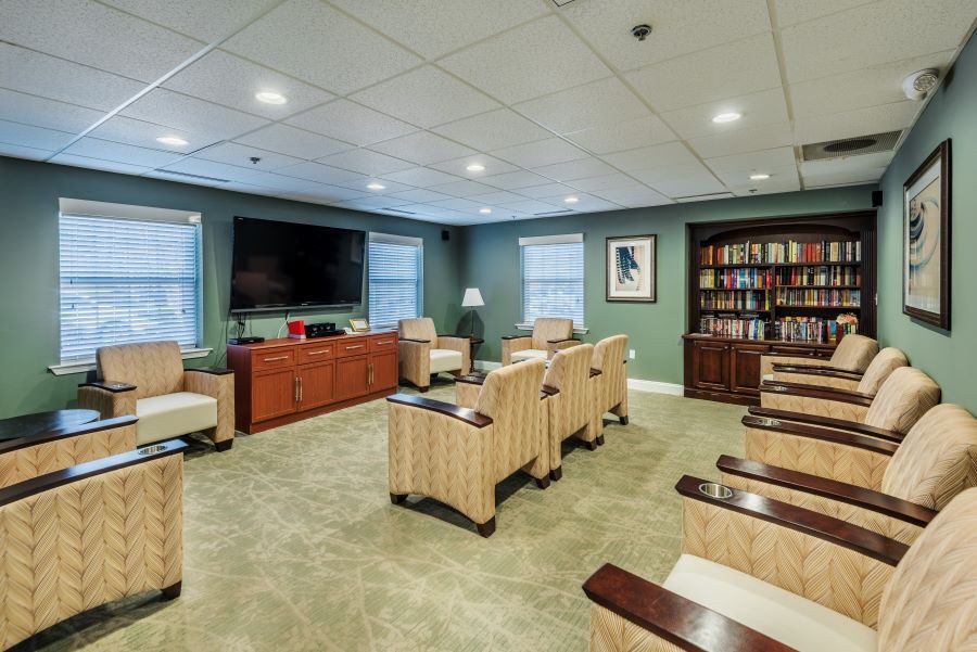 A cozy room with comfortable seating, a large television, and a bookshelf.