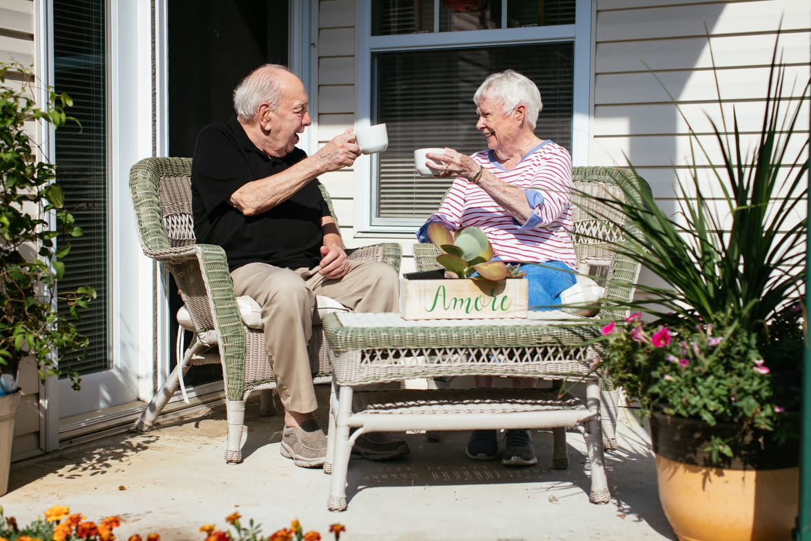An elderly couple enjoying tea on their porch.