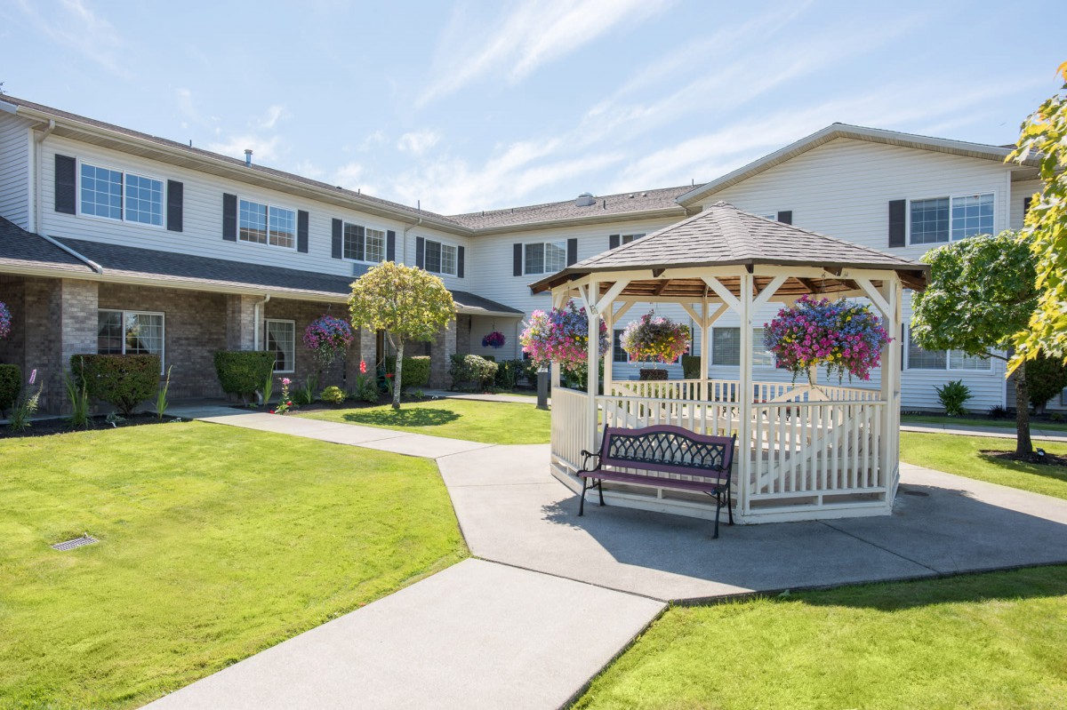 A well-maintained garden with a gazebo in front of a residential building.