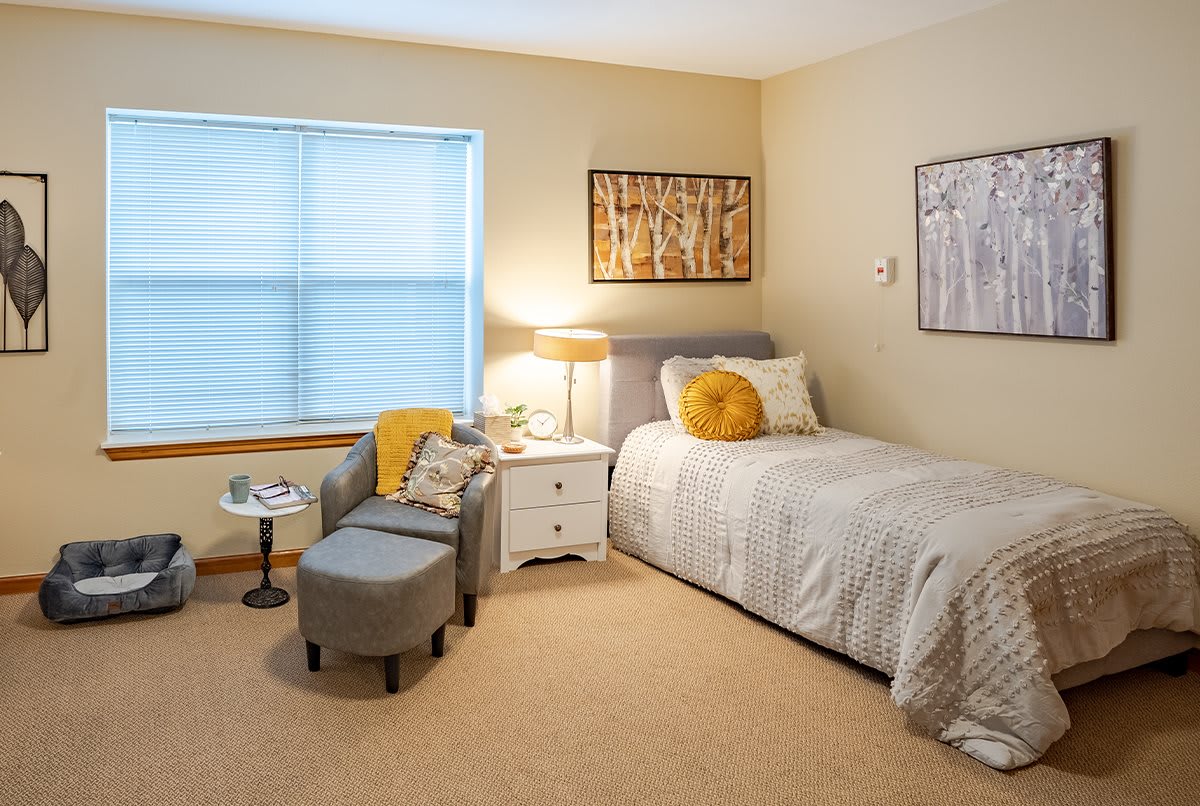 A cozy bedroom with a single bed, armchair, and soft lighting.