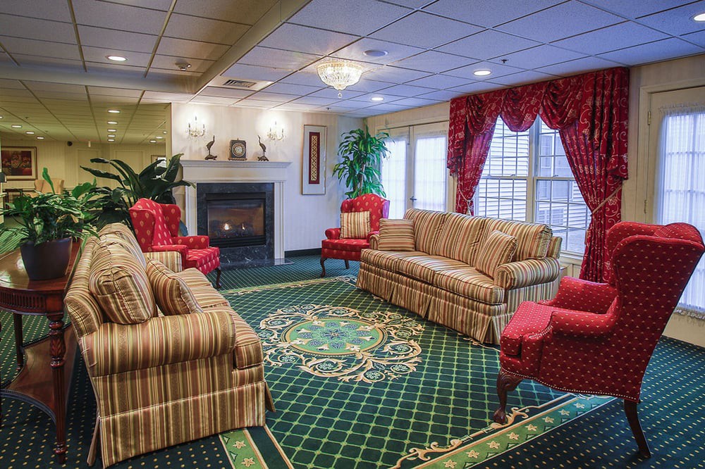 A traditionally decorated living room featuring a fireplace, patterned sofas, and elegant curtains.