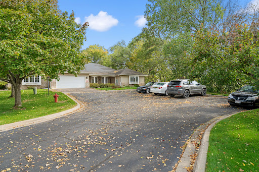 A peaceful suburban home with a spacious driveway surrounded by lush greenery.