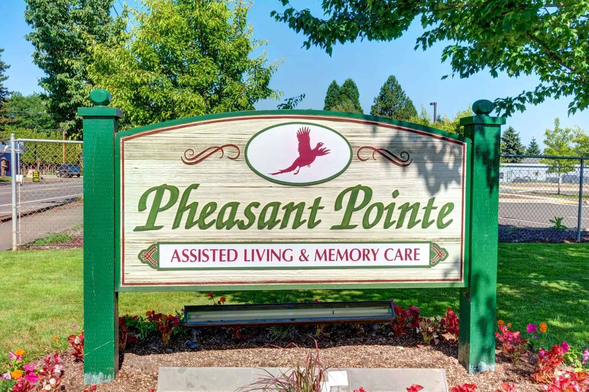 Sign for Pheasant Pointe, an assisted living and memory care facility, surrounded by trees.