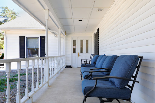 A cozy porch featuring comfortable seating with blue cushions and a welcoming entrance.