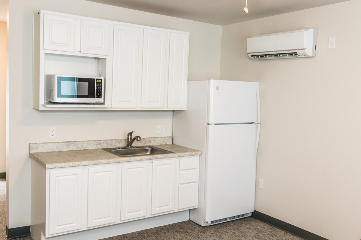 A modern kitchen with white cabinets, a refrigerator, microwave, and sink.