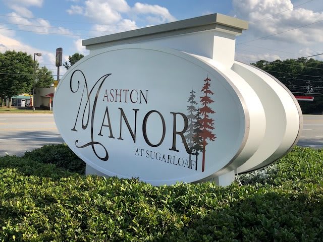 The Ashton Manor sign stands prominently in a landscaped area.
