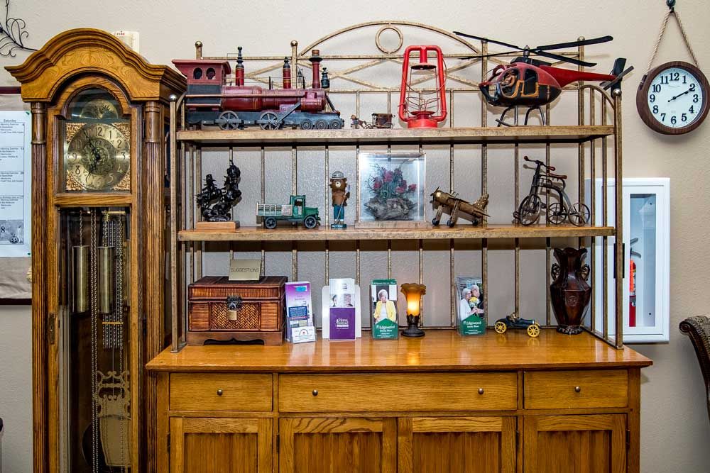 A wooden cabinet with shelves displaying model trains, a helicopter, figurines, and brochures.