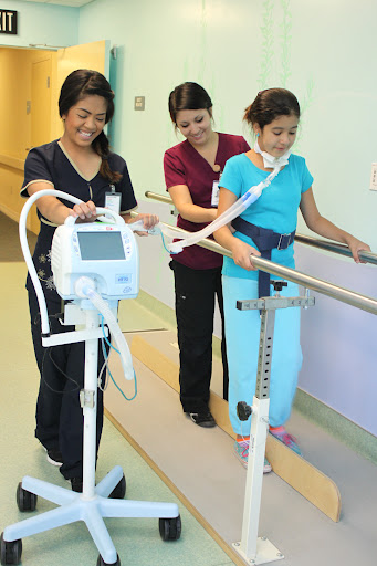 Healthcare professionals assisting a patient during physical therapy to improve mobility.