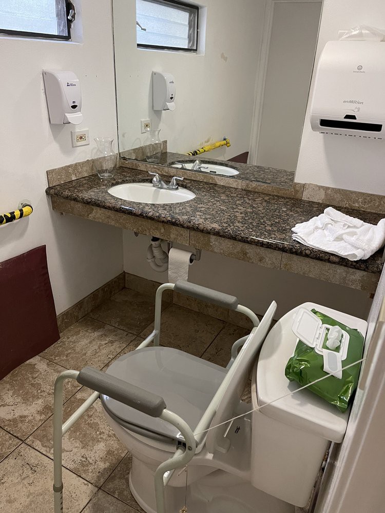 An accessible bathroom with a sink and grab bars, featuring a chair for assistance.