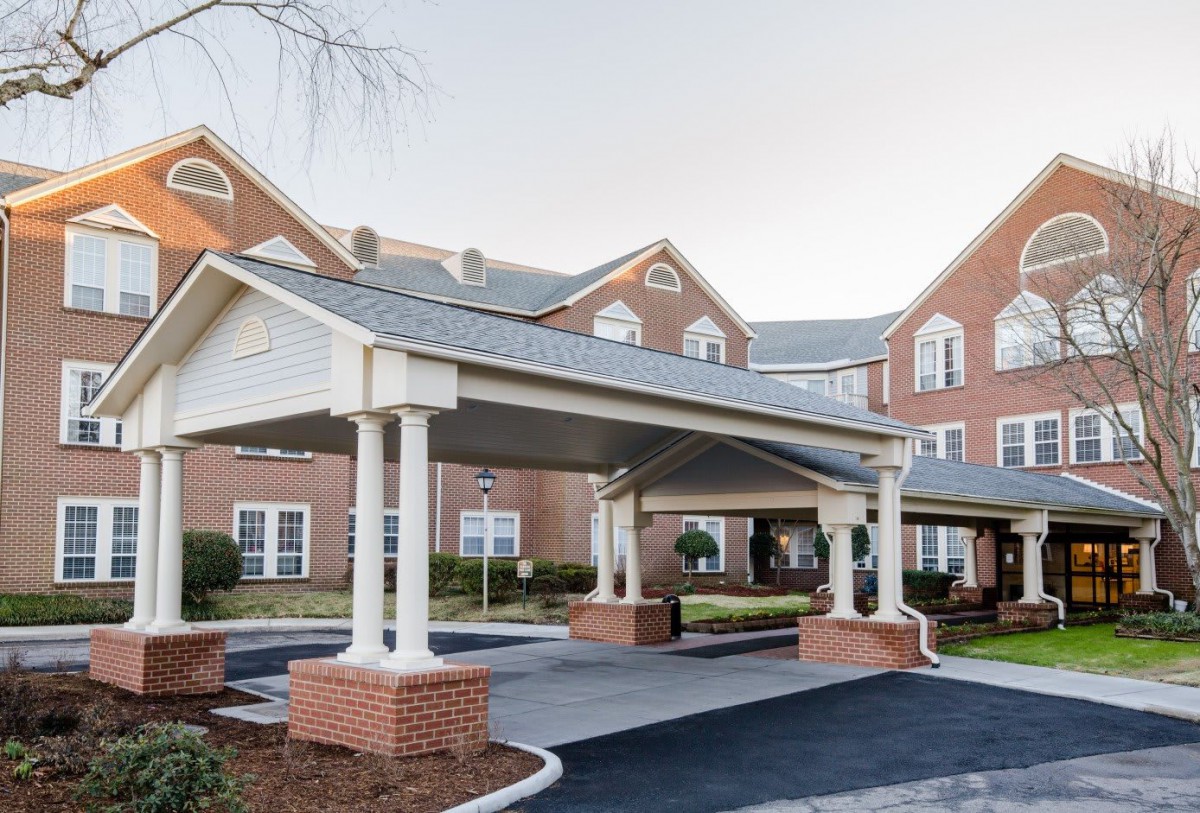 A brick building with a covered entrance and multiple windows, showcasing residential architecture.