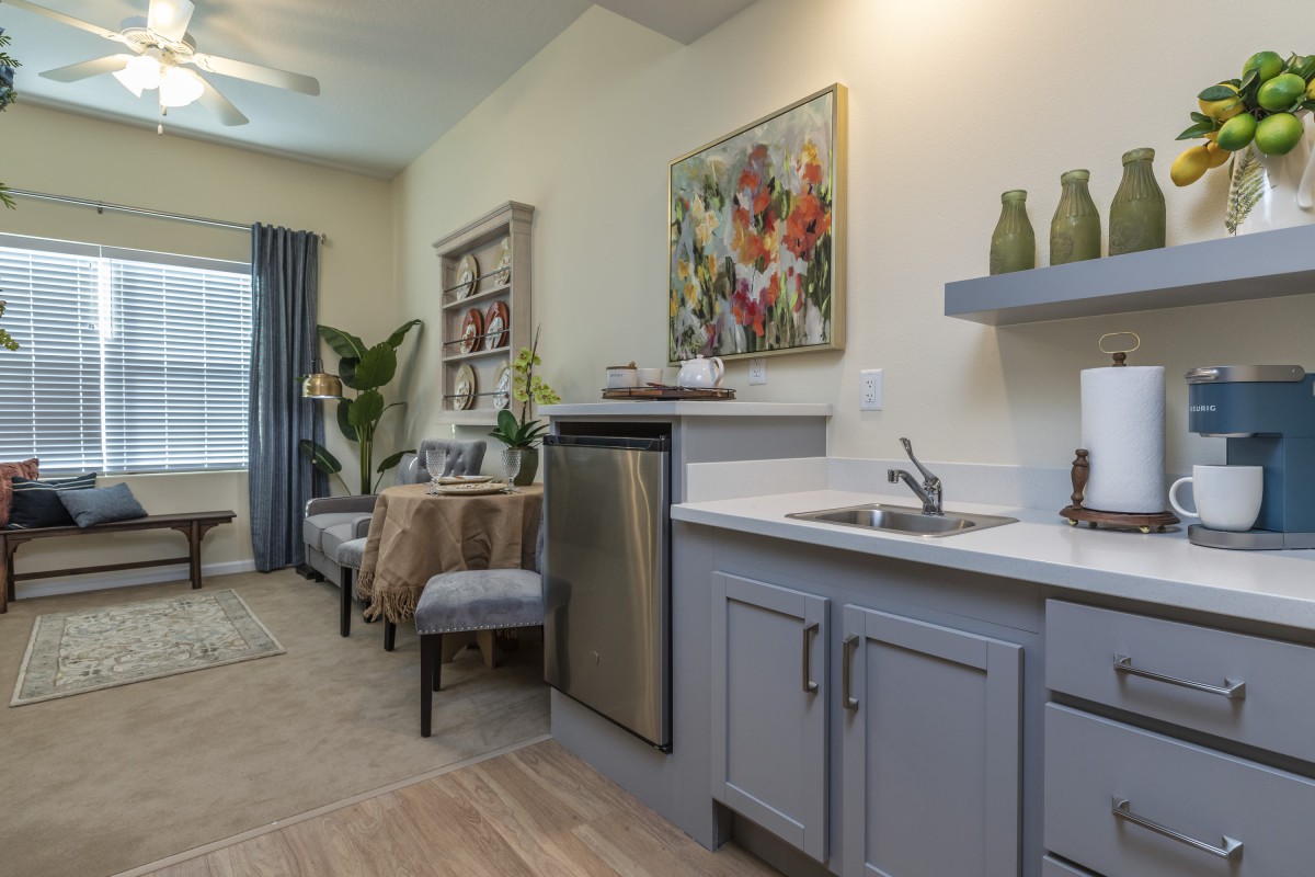 A modern apartment kitchen with a cozy dining area and colorful artwork on the wall.