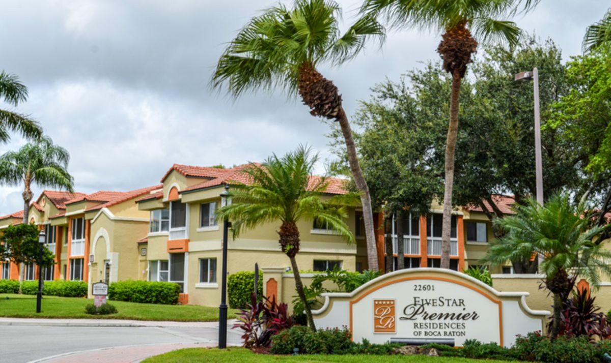 A scenic view of a resort entrance with palm trees and lush greenery.