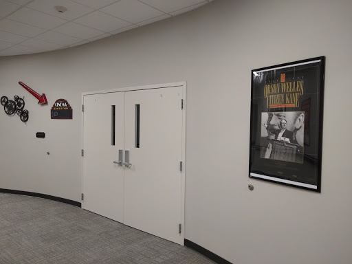 A view of a hallway featuring a pair of doors and a framed poster on the wall.