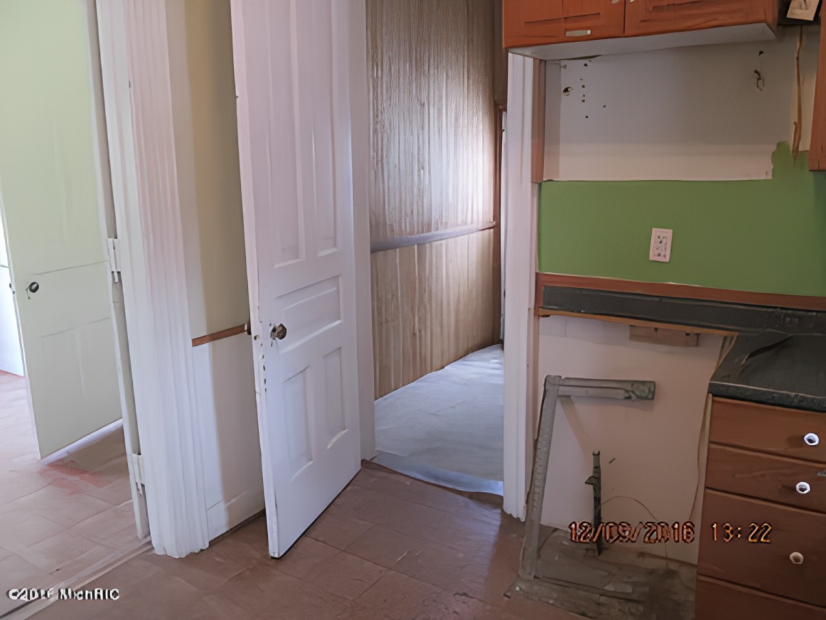 An unfinished interior space with a partially open door leading to another room.