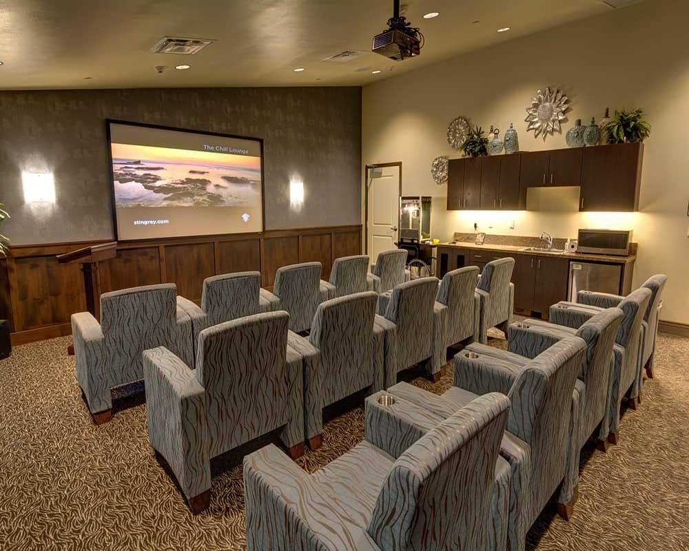 A cozy home theater with rows of plush seats facing a large screen.