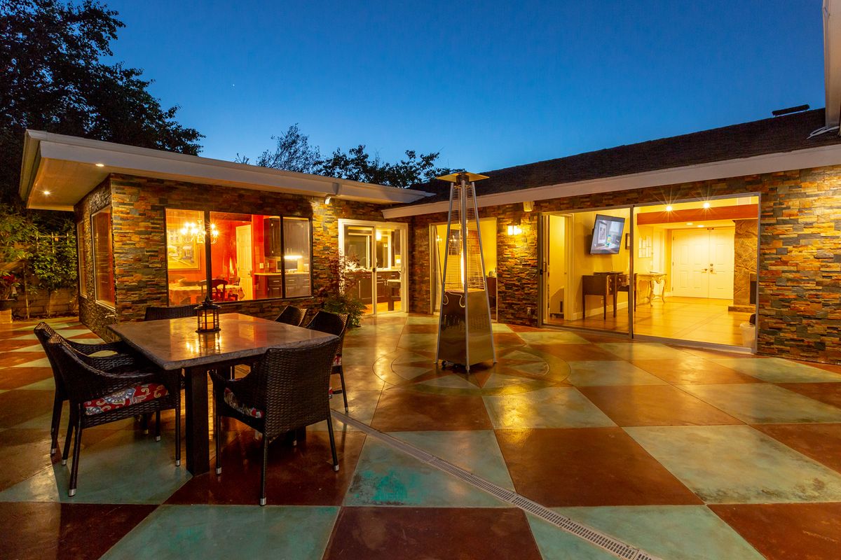 A modern outdoor patio with warm lighting, featuring furniture and a cozy atmosphere during the evening.