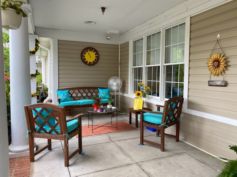 A cozy porch with vibrant teal-cushioned furniture and cheerful decor.