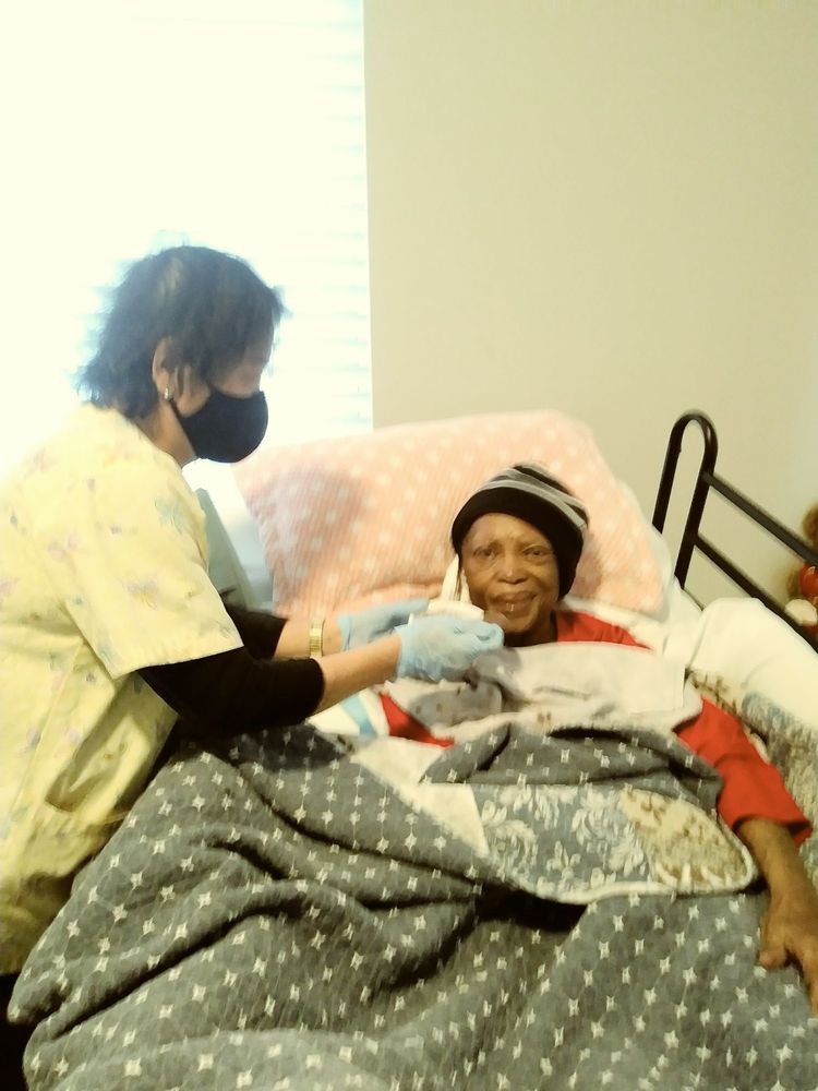 A nurse providing care to an elderly patient in a hospital bed.