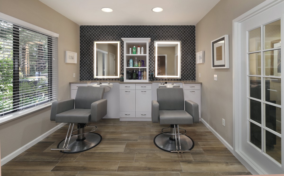 A modern hair salon interior with two styling stations and illuminated mirrors.