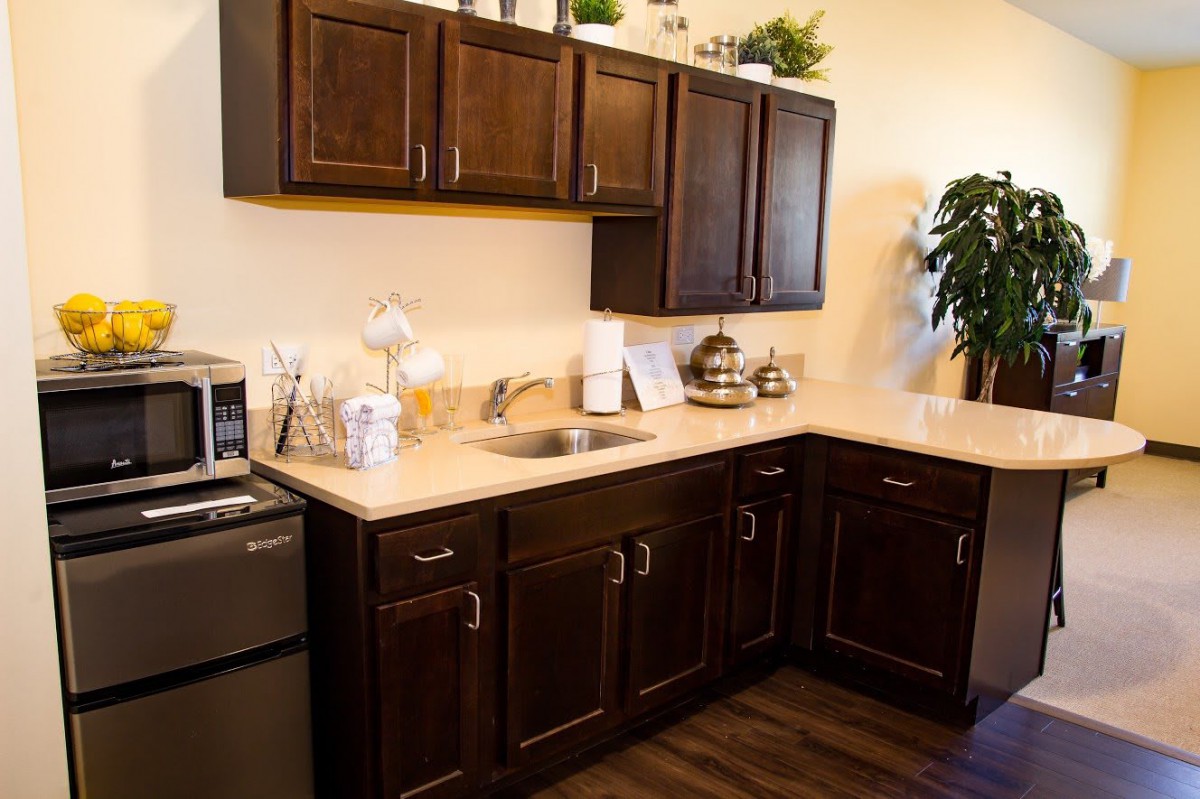 A modern kitchen with dark wooden cabinets and a small countertop featuring various appliances and decor.