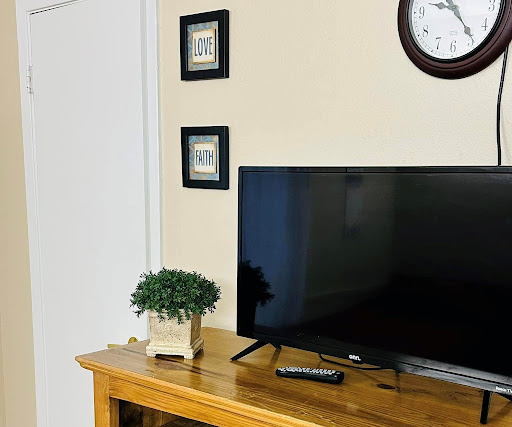 A cozy living room setup featuring a television on a wooden console, accompanied by decorative frames and a small plant.