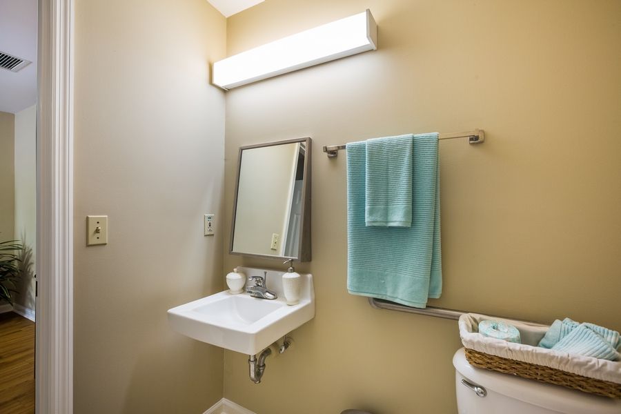 A clean and simple bathroom with a wall-mounted sink, mirror, and teal towels.