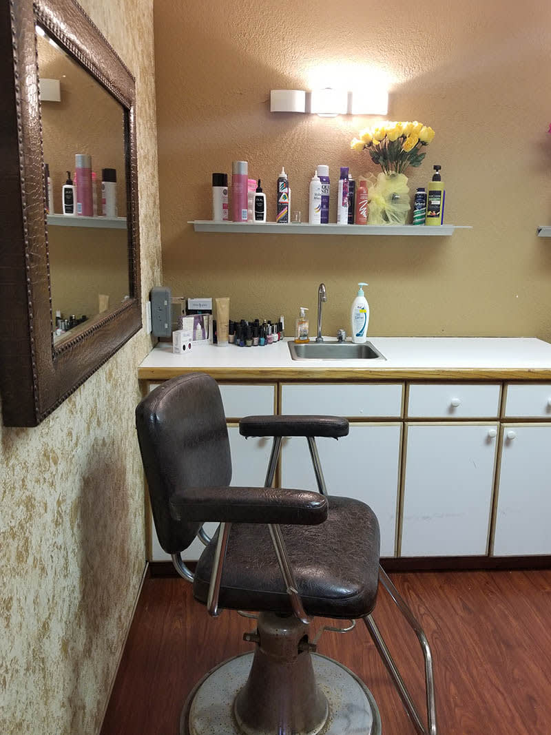 A cozy salon setup featuring a barber chair, mirror, and a variety of hair products on shelves.