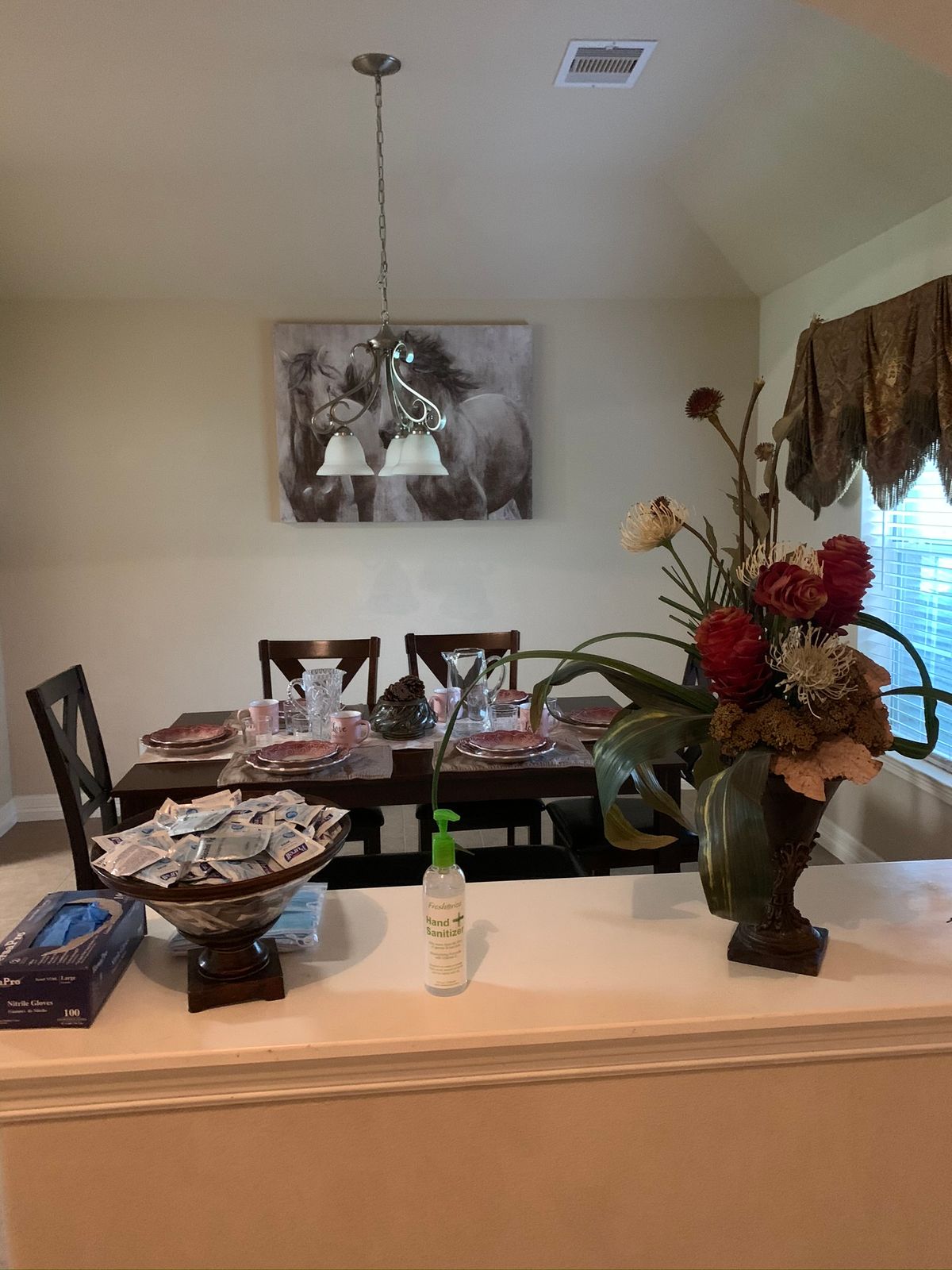 A well-decorated dining room with a table set for a meal, featuring a floral arrangement and artwork on the wall.