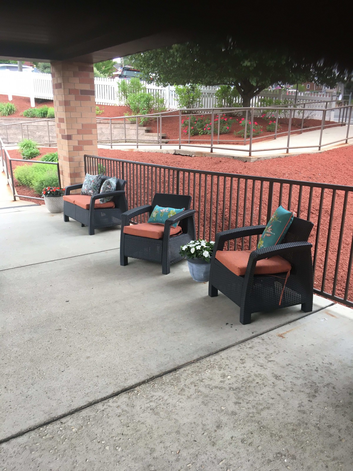 Outdoor patio area with cushioned chairs and a railing.