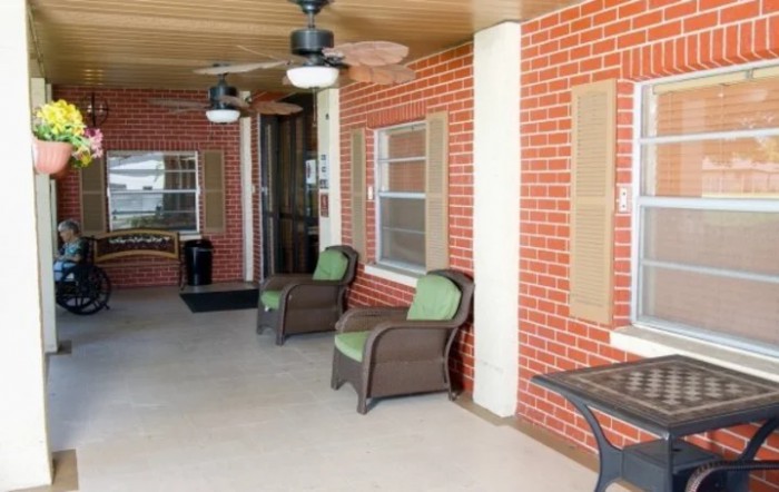 A cozy porch area with wicker chairs, brick walls, and ceiling fans.