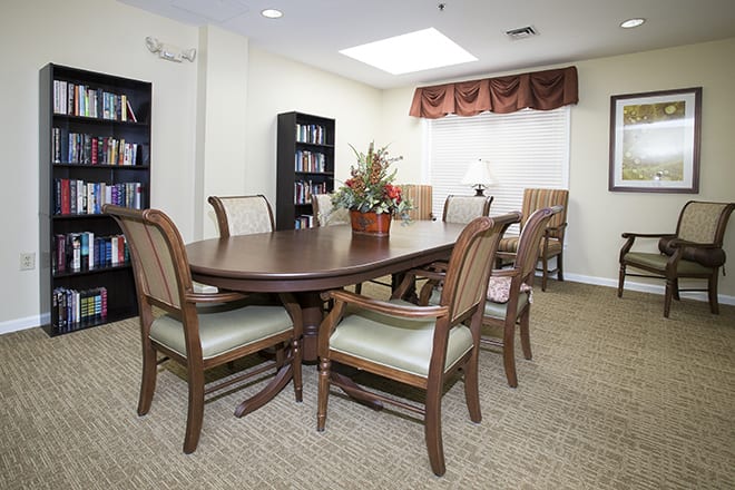 A conference room with a wooden meeting table, surrounded by chairs and library shelves.