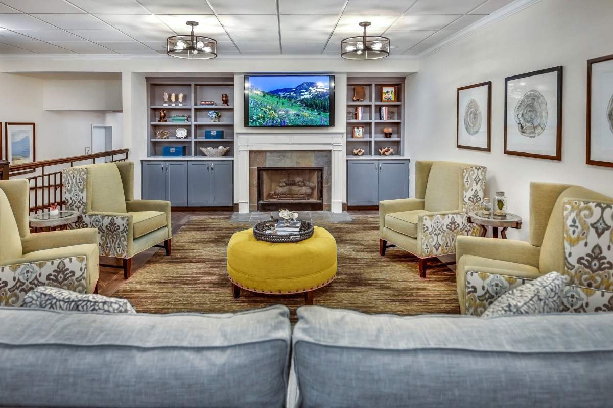 A modern living room with stylish furniture, a fireplace, and a television above built-in bookshelves.