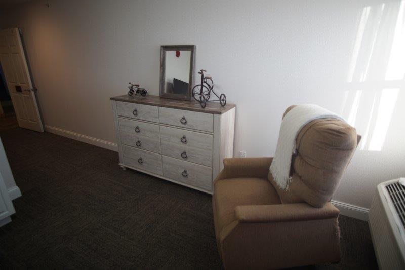 A cozy room with a dresser and an armchair.