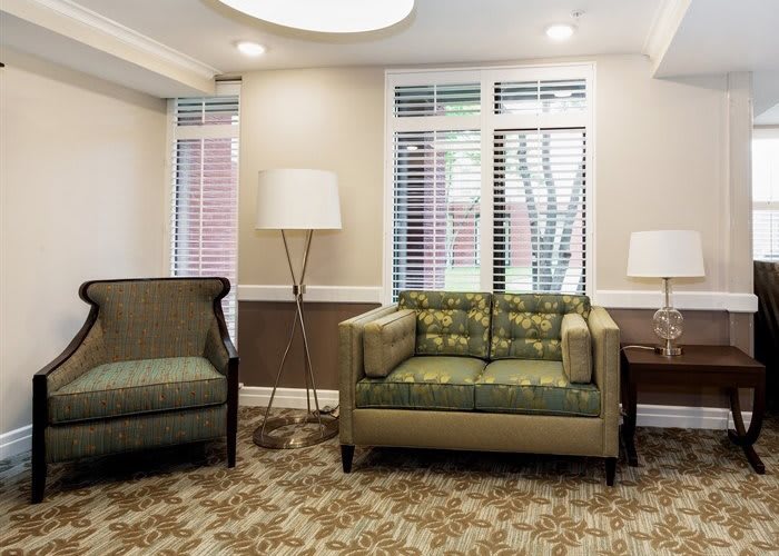 A cozy living room with sofas, lamps, and large windows.