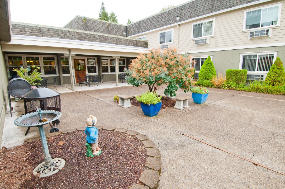 A peaceful courtyard with benches and potted plants in front of a building.
