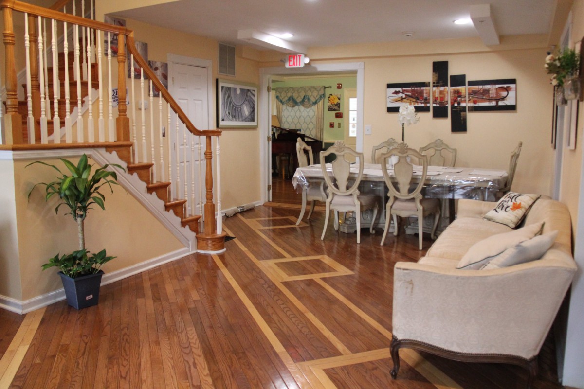 A cozy living and dining area with wooden floors, elegant furniture, and a staircase.
