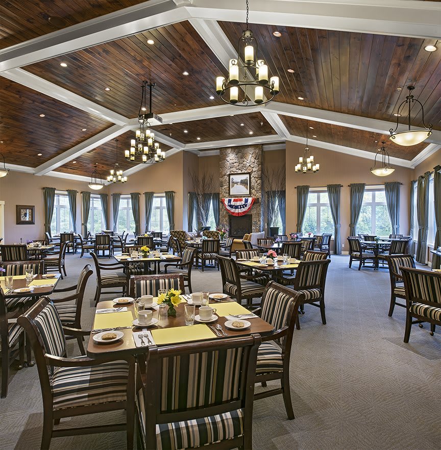 An elegant dining room with neatly arranged tables and chandeliers.
