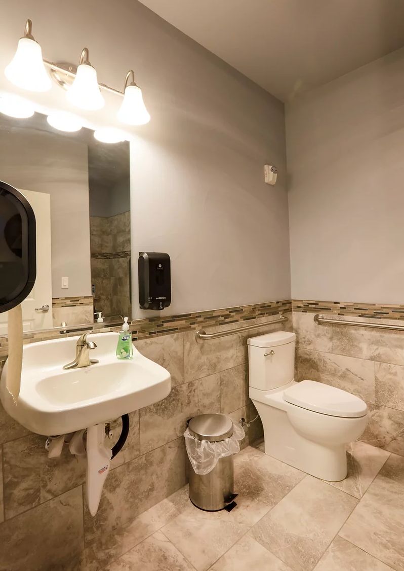 A clean and modern bathroom with a sink, toilet, and mirror.