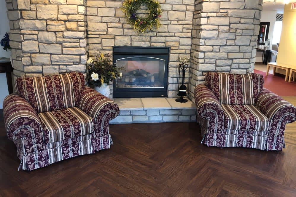Cozy living room with a stone fireplace and striped chairs.