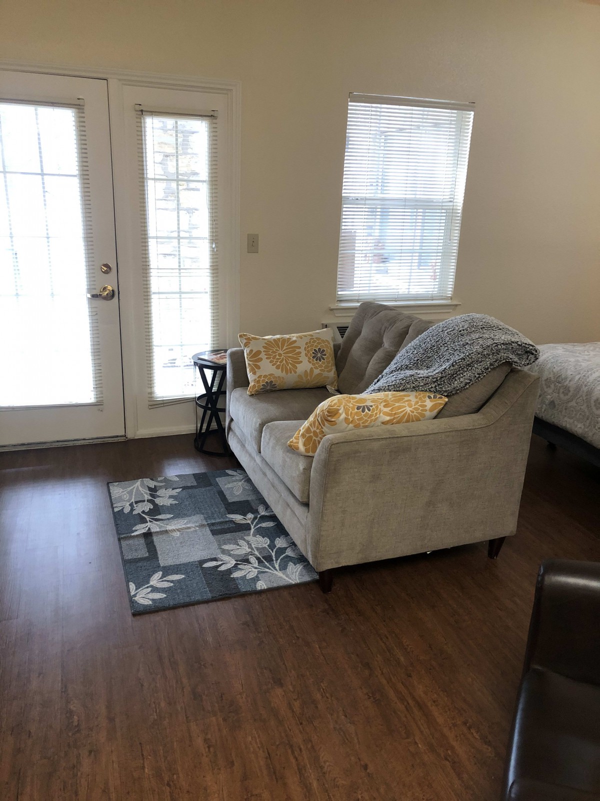 A cozy living space with a sofa, cushions, and decorative rug on a wooden floor.