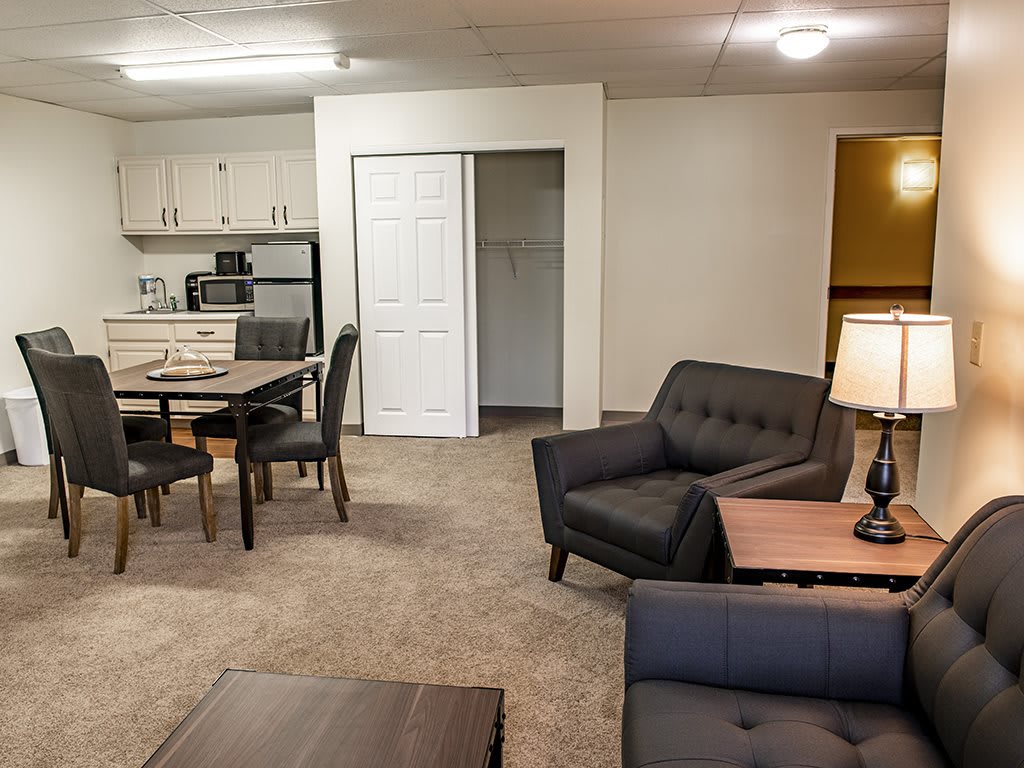 A modern apartment interior featuring a living room area with sofas, a dining table, and an open kitchen space.