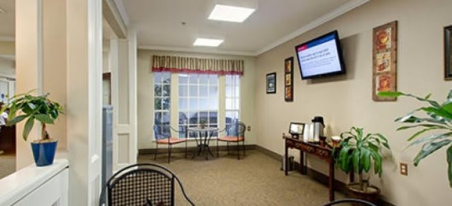 A waiting room with chairs, a table, television, and a coffee station.