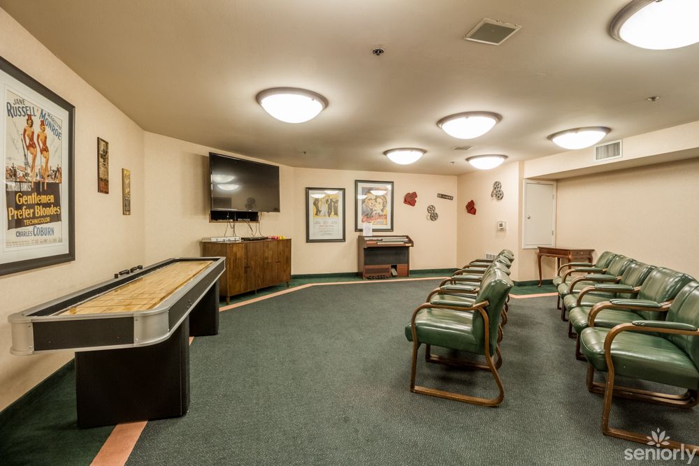 A cozy game room featuring a shuffleboard table, multiple chairs, and a television.