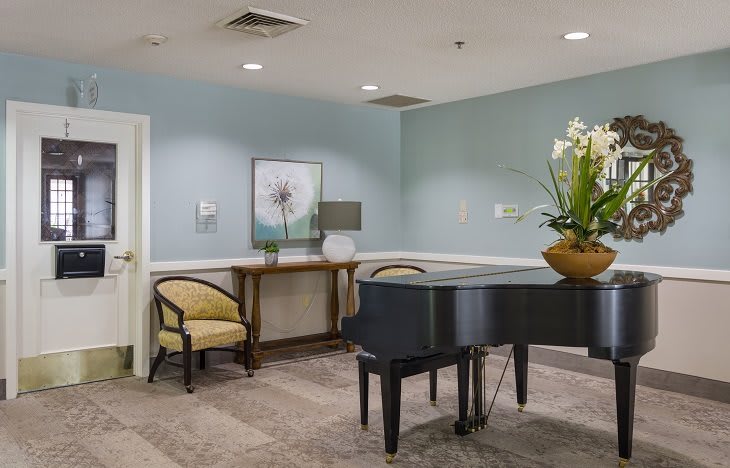A cozy interior with a piano, chairs, and decorative elements including artwork and plants.