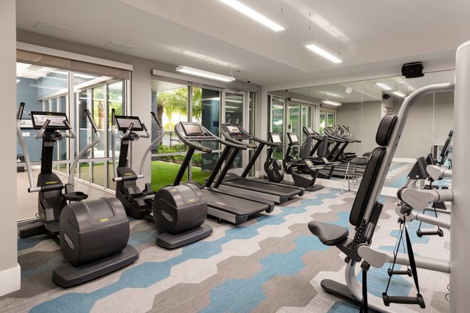 A modern gym with treadmills, stationary bikes, and various exercise equipment.